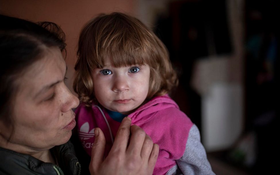 Ukraine: Ein Mädchen auf dem Arm ihrer Mutter schaut in die Kamera.