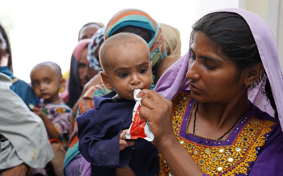 Ein Kind auf dem Arm der Mutter wird mit Erdnusspaste gefüttert.