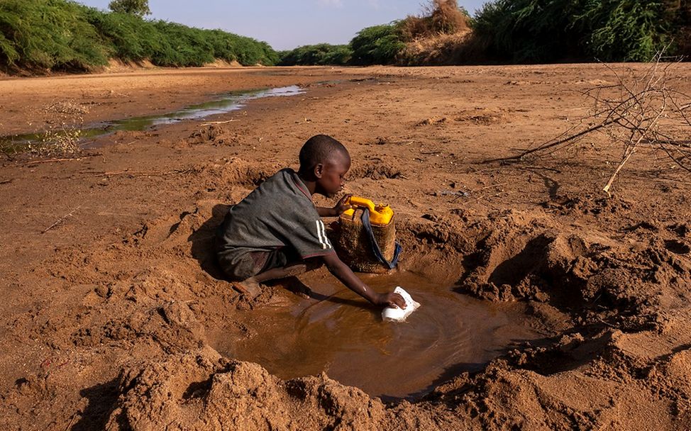 Äthiopien: Ein Junge schöpft Wasser aus einer Pfütze in einen Kanister.