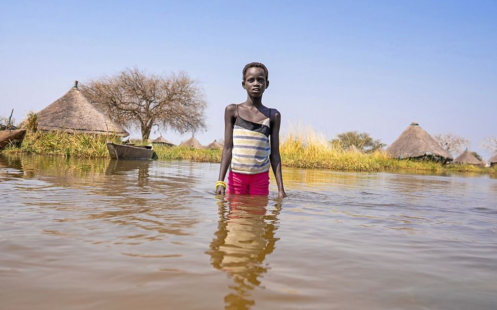 Südsudan: Ein Junge steht knietief im Wasser und schaut frontal in die Kamera.