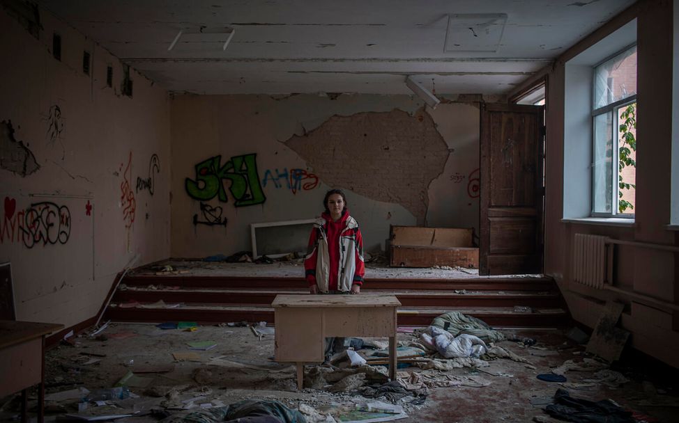 Darya steht in ihrem zerstörten Klassenzimmer in der Ukraine.