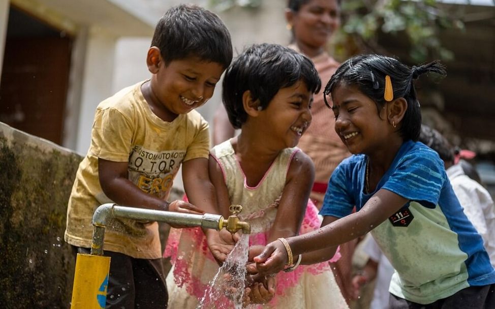 Ramanagara: Drei Kinder waschen sich im Freien die Hände.