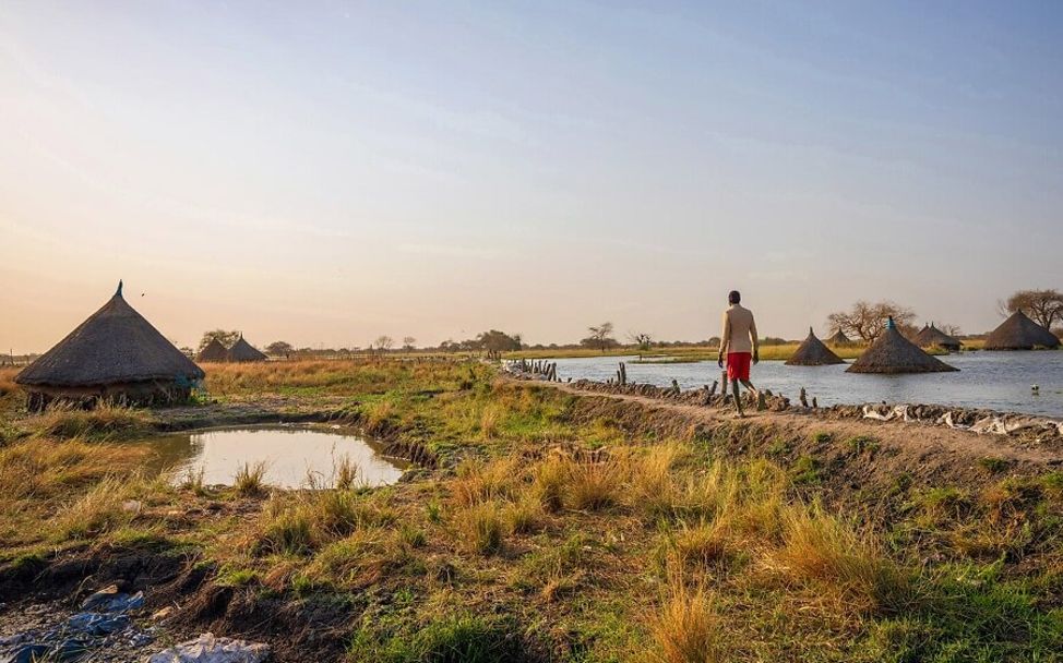 Südsudan: Ein Junge läuft über einen Damm, der Häuser vor der Flut schützen soll.