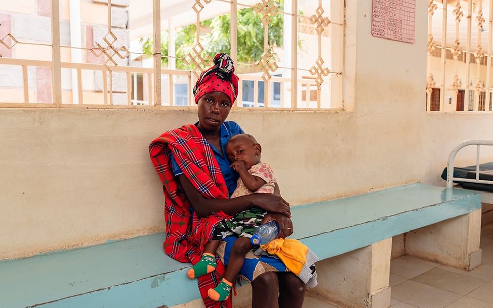 Kenia: Mutter mit Kind auf dem Schoß in einem Ernährungszetrum in Garissa