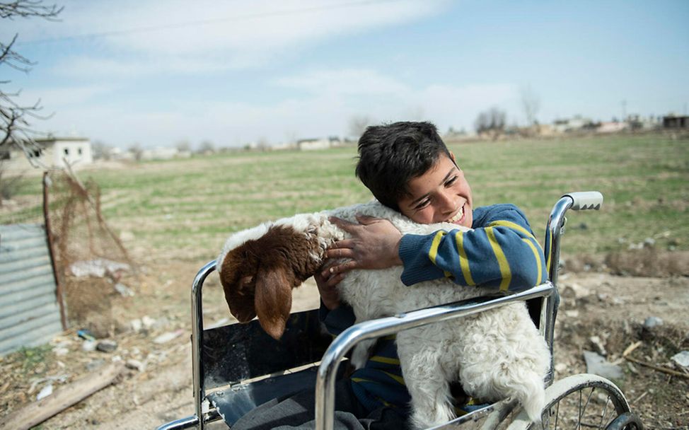 Syrien: Ein im Rollstuhl sitzender Junge streichelt eine Ziege | © UNICEF/Belal