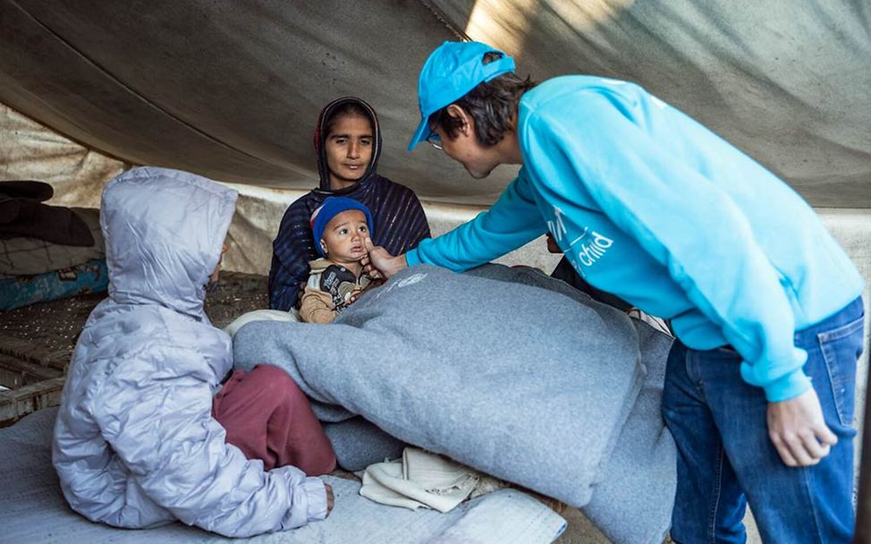 Pakistan Überschwemmungen: Ein UNICEF-Mitarbeiter übergibt einer Familie Hilfsgüter für den Winter.