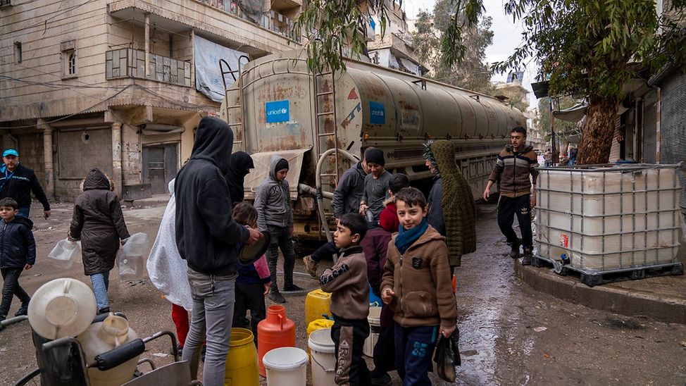 Erdbeben in Syrien: Menschen warten vor einem LKW auf Trinkwasser.