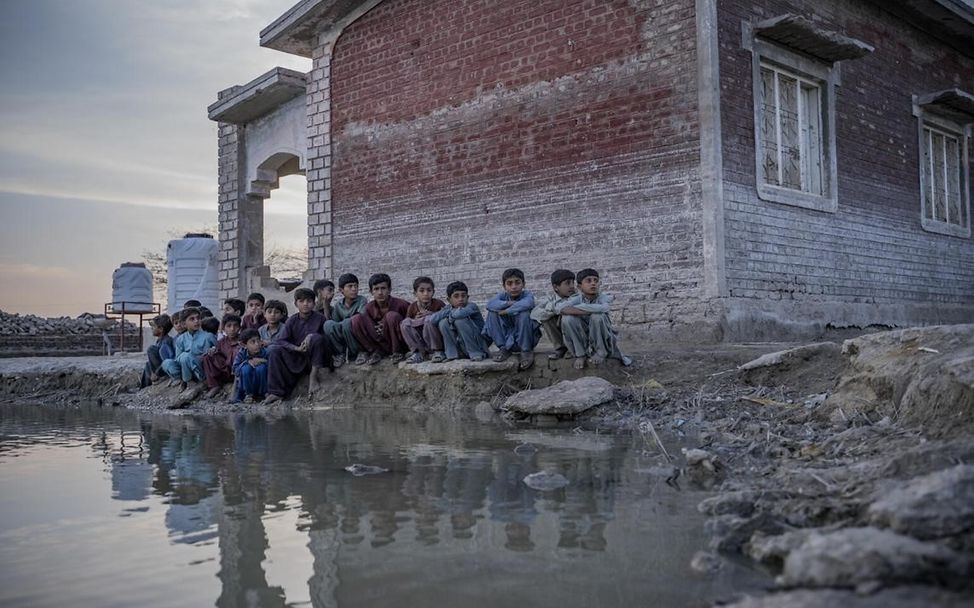 Kinder sitzen am Rande eines überfluteten Gebietes im Distrikt Dadu, in der Provinz Sindh.