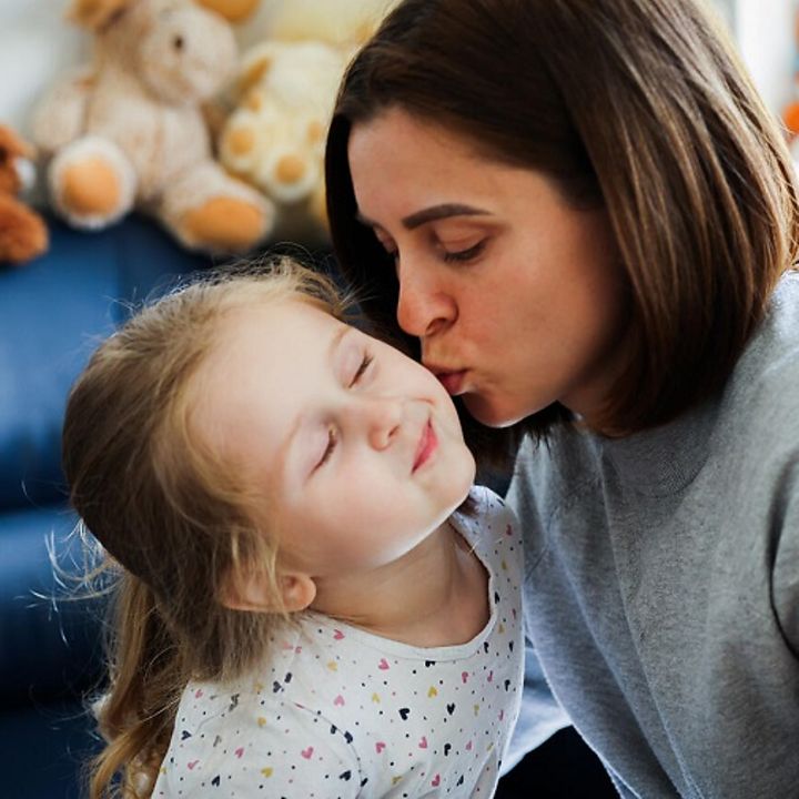 Natalia gibt ihrer Tochter einen Kuss auf die Wange.