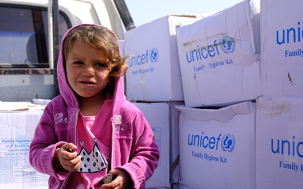 Syrien: Kind steht vor UNICEF-Hilfsgütern.