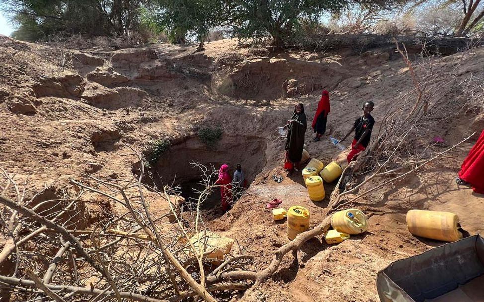 Afrika: Menschen sind auf der Suche nach Wasser in einem ausgetrockneten Flussbett.