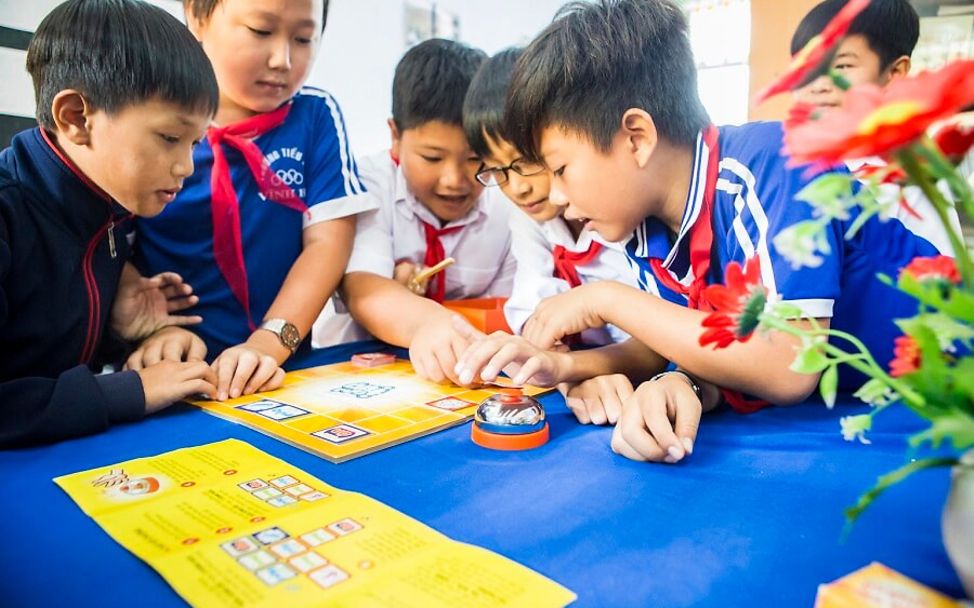 Vietnam: Schulkinder spielen ein Spiel an einem Tisch.