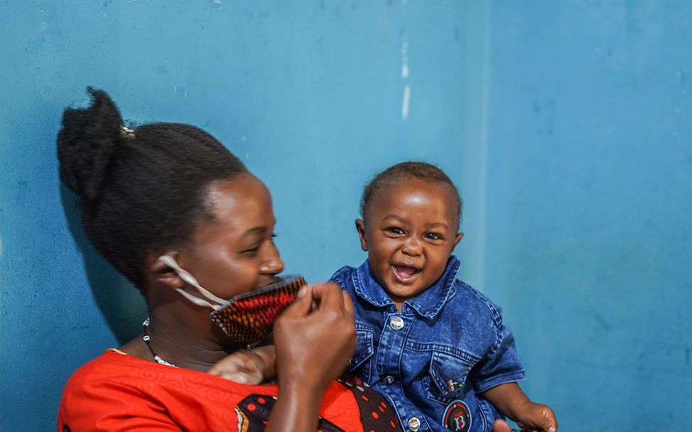 Corona: Eine Mutter in Uganda spielt mit ihrem Baby, während sie auf eine Corona-Schutzimpfung wartet. 