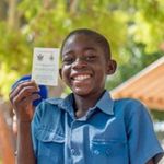 Tichaona aus Zimbabwe zeigt stolz seinen Impfausweis. 