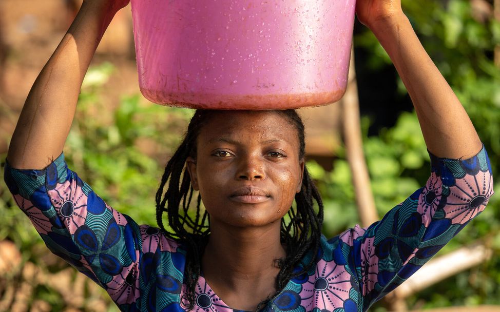 Im Kampf gegen Cholera schöpft Souza Mbomba (19) Wasser aus  einer von UNICEF erschlossenen Wasserquelle.