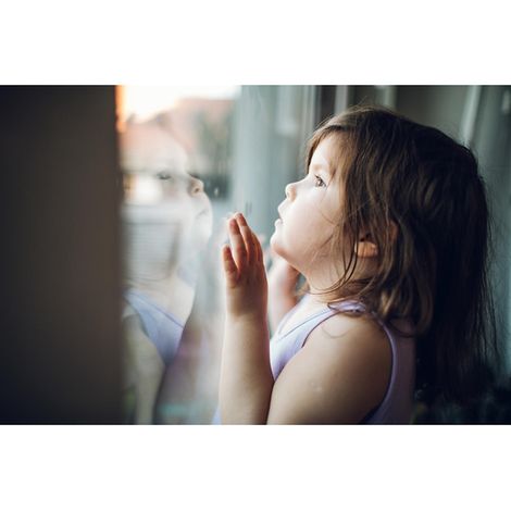 3 Jahre Corona: Mädchen schaut aus dem Fenster