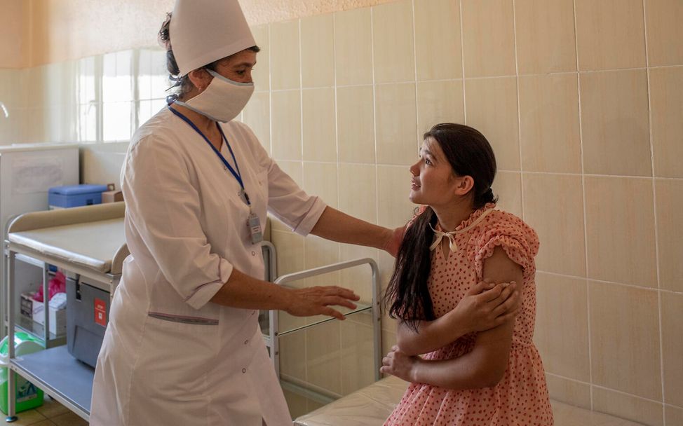 Shakhrizoda hört ihrer Krankenschwester Djuraeva genau zu, bevor sie die erste Dosis des HPV-Impfstoffs erhält. 