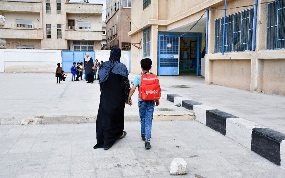 Syrien: Ahmad geht mit seiner Mutter Hand in Hand über den Schulhof.