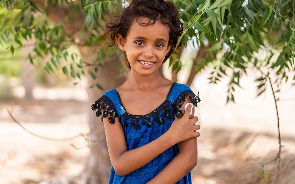 Jemen: Ein Mädchen drückt nach einer Impfung mit dem Finger auf ein Pflaster auf ihrem Oberarm.