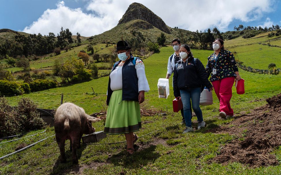 María führt eine Gruppe von Ärzt*innen zum Haus eines Mädchens, das geimpft werden muss. 