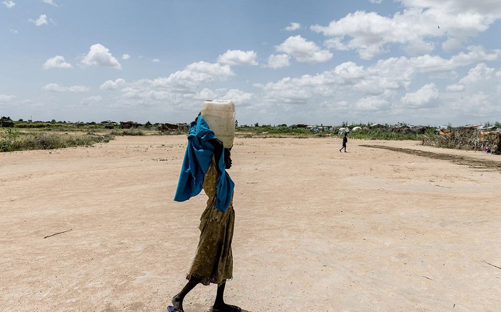 Sudan: Mädchen trägt Wasser in einem Kanister über dem Kopf.