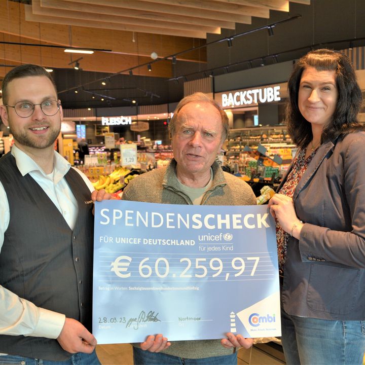 Herr Bartinger (in der Mitte) nimmt den symbolischen Scheck im Combi-Verbrauchermarkt Remels entgegen.