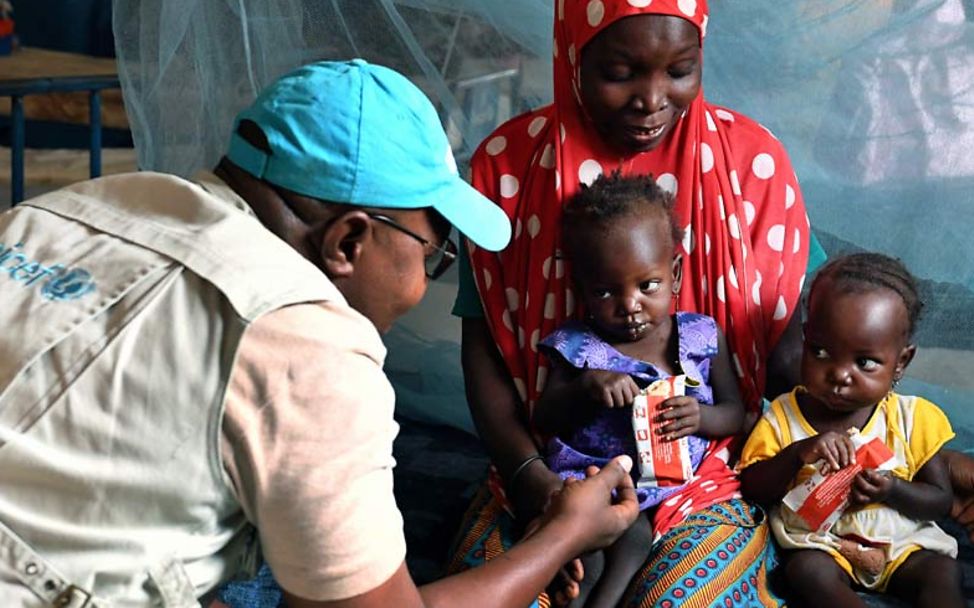 Niger Unterernährung: Ein UNICEF-Helfer im Gespräch mit unterernährten Kleinkindern. 