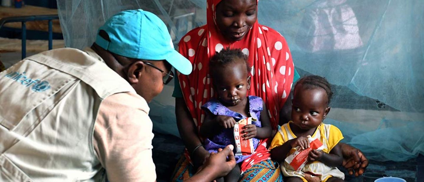 Niger Unterernährung: Ein UNICEF-Helfer im Gespräch mit unterernährten Kleinkindern. 
