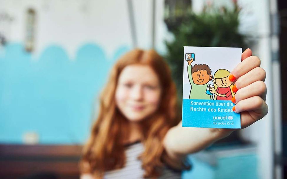 70 Jahre UNICEF Deutschland: Ein Mädchen zeigt eine Broschüre zur Kinderrechts-Konvention