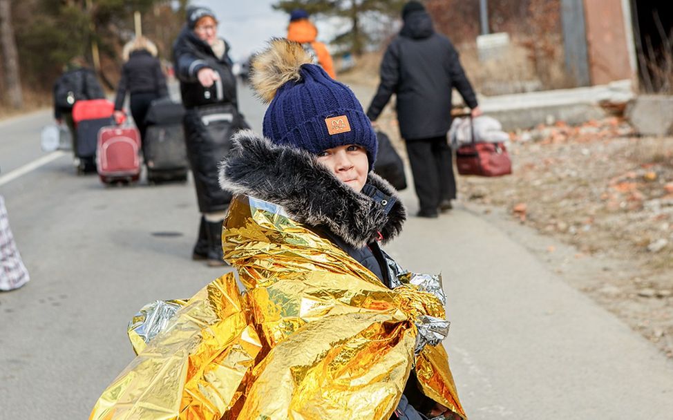 Ukraine: Ein Kind mit einer Wärmedecke um den Körper steht auf einem Weg und dreht sich um.