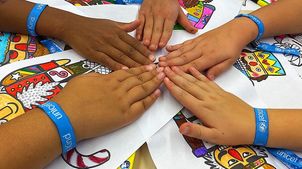 Malsch: Kinder von der Waldhausschule halten ihre Hände in die Mitte. Sie tragen ein blaues UNICEF Band um das Handgelenk.