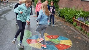 Greven: Schüler*innen spielen auf dem Schulhof ein Hüpfspiel