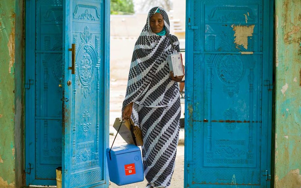 Sudan Nothilfe: Eine Impfhelferin kommt mit ihrer Kühlbox in einer Flüchtingsunterkunft an. 
