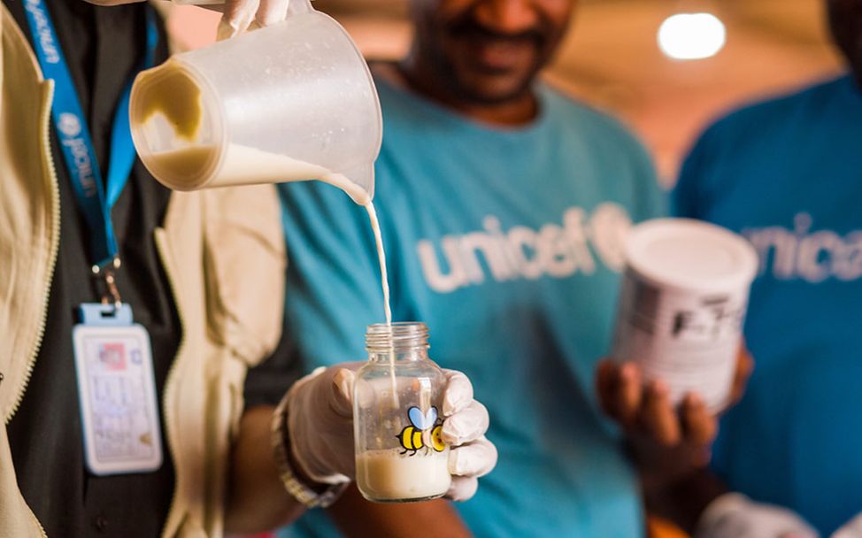 Sudan Nothilfe: Ein UNICEF-Helfer bereitet eine Flasche mit therapeutischer Milch für ein mangelernährtes Kleinkind vor. 