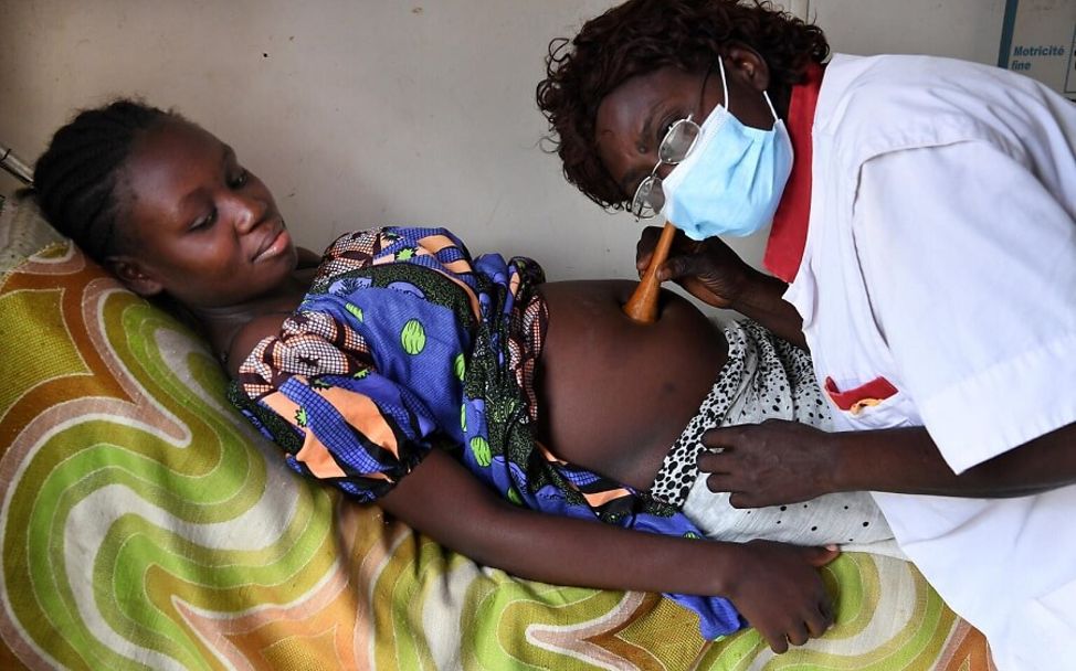 Kongo: Eine Schwangere liegt auf einem Krankenhausbett und eine Ärztin hört ihren Bauch ab.