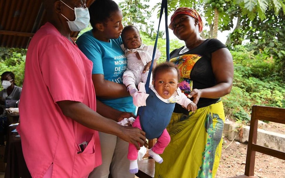 Kongo: Ein Baby hängt in einem Gurt, um gewogen zu werden.