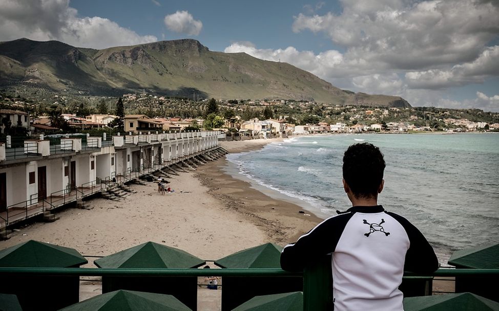 Italien: Ein Junge steht auf einem Steg und schaut Richtung Meer.