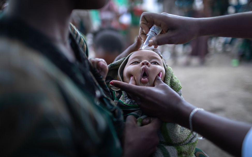 Äthiopien: Ein Kind auf dem Arm seiner Mutter erhält eine Schluckimpfung.