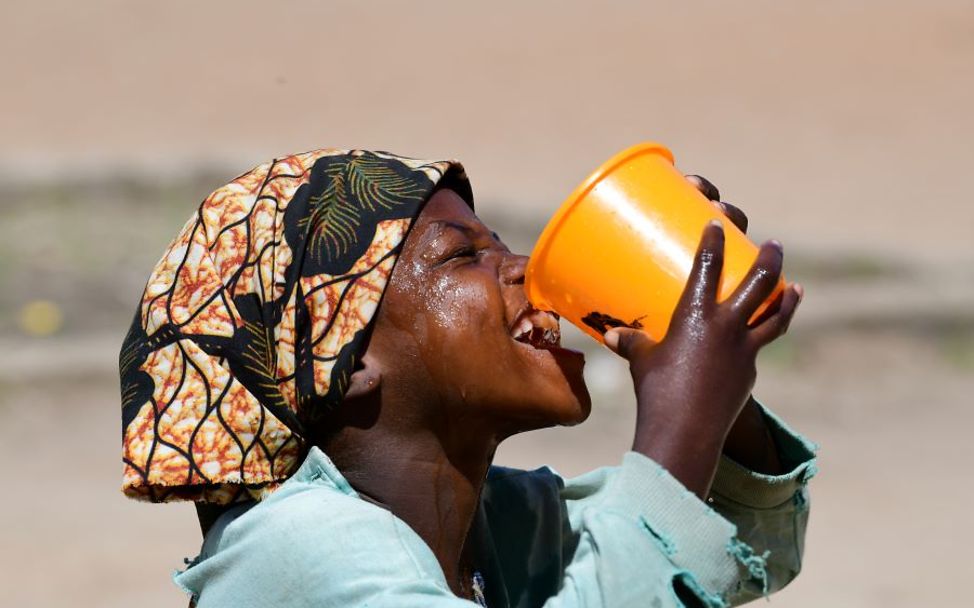 Ein Mädchen trinkt Wasser aus einem großen Becher