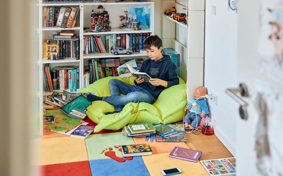 Junge liest in seinem Zimmer im Schutz vor der Hitze