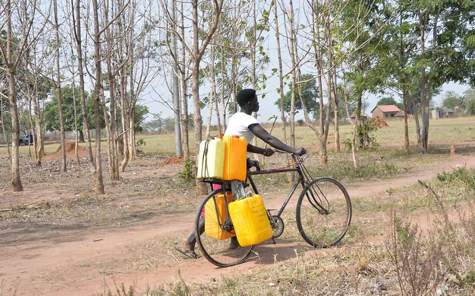 Jane (30) transportiert Kanister mit sauberem Wasser zur Grundschule