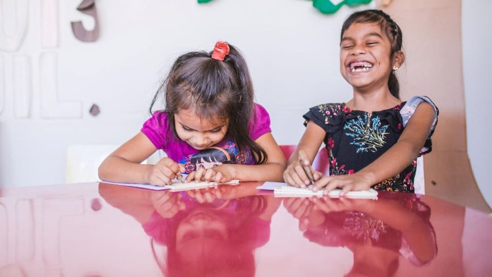 Guatemala: Zwei Schulmädchen sitzen an einem Tisch und lösen Aufgaben.