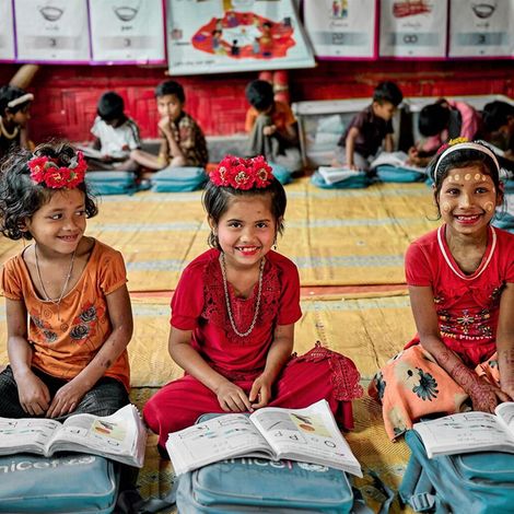 Rohingya-Mädchen posieren fröhlich für ein Foto im von UNICEF unterstützen Lernzentrum in Cox Basar in Bangladesch. 