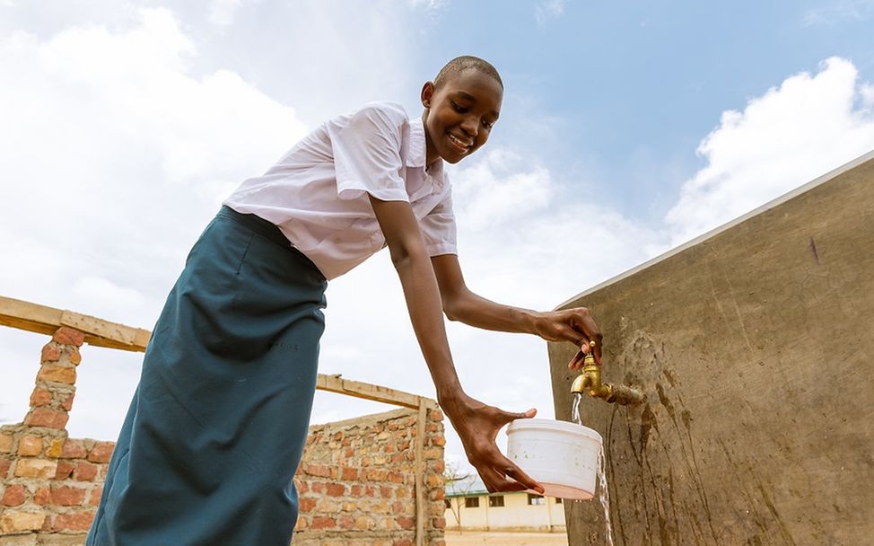 Kenia: Ein Mädchen befüllt einen Eimer mit Wasser.