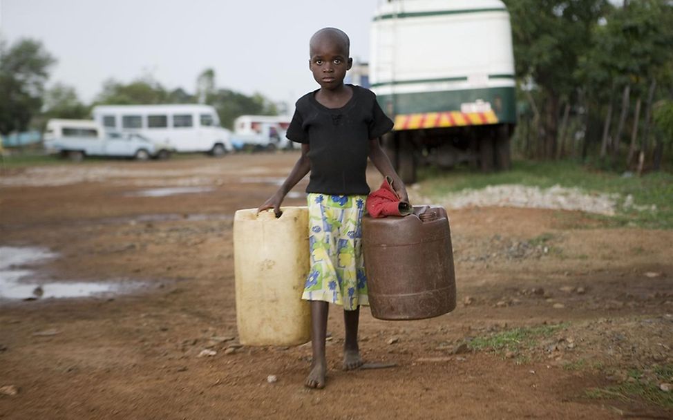 Ein Mädchen trägt Kanister mit von UNICEF bereitsgestelltem 