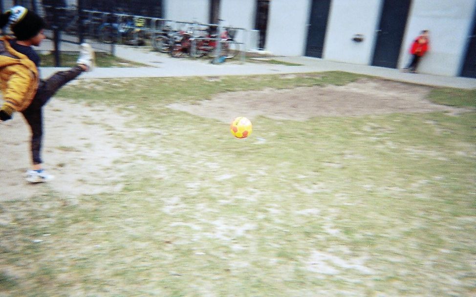 Geflüchtete Kinder in Deutschland: Ein Junge spielt Fußball in einer Flüchtlingsunterkunft 