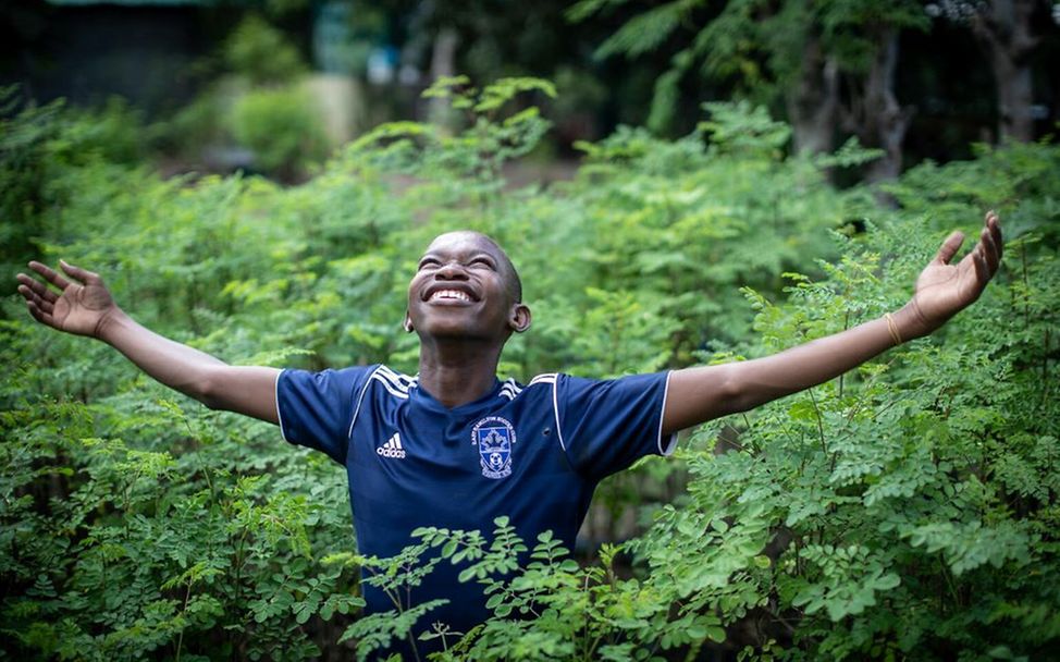 Haiti: Junge steht im Wald und freut sich über Regen.