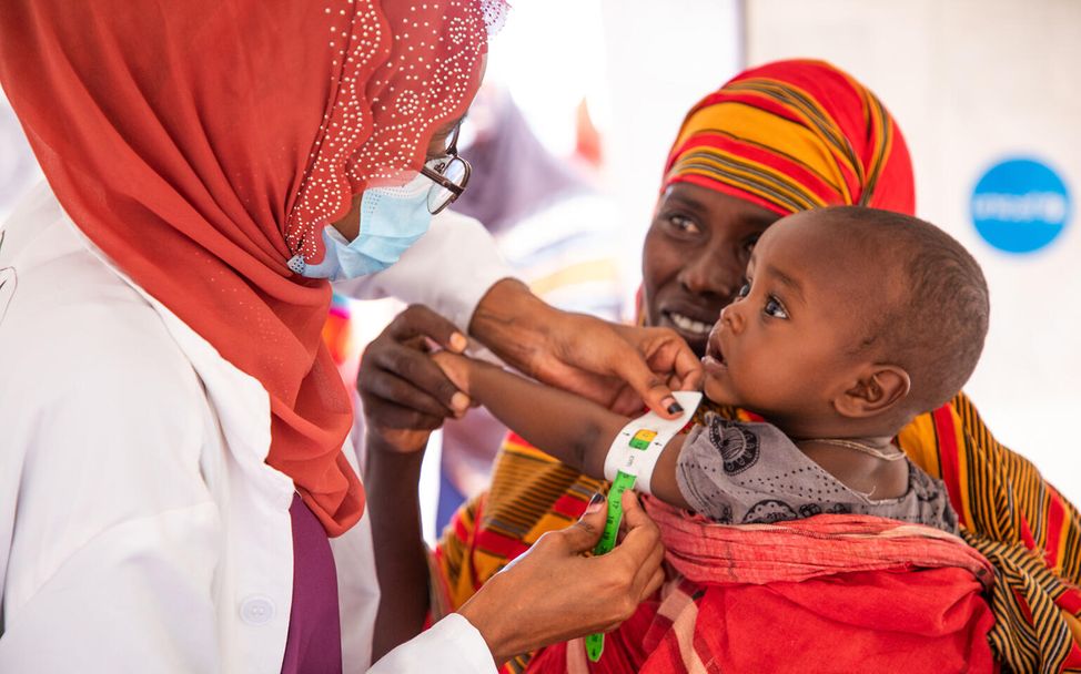Spenden statt schenken Unternehmen: Eine Helferin untersucht ein Kind auf Mangelernährung in Äthiopien