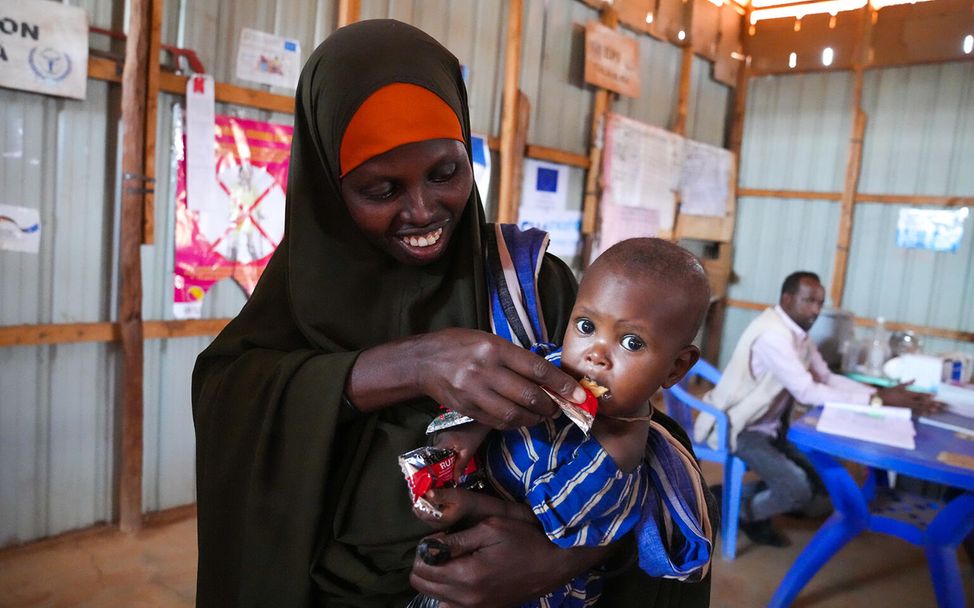 Spenden statt schenken Unternehmen: Eine Mutter füttert ihr Kind mit Erdnusspaste in Somalia