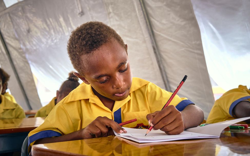 Spenden statt schenken Unternehmen: Ein Junge lernt in einer Notschule in Vanuatu in einem Zelt